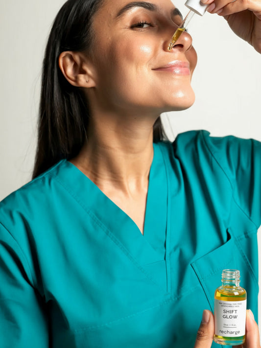 Nurse in teal scrubs applying ShiftGlow Recharge serum with dropper, a bakuchiol retinol alternative that soothes redness, calms maskne, and restores glow.
